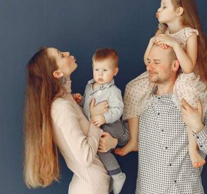 Portrait of a joyful family with parents and kids showing love and affection against a blue background.