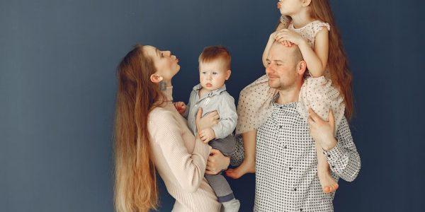 Portrait of a joyful family with parents and kids showing love and affection against a blue background.