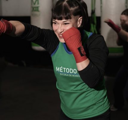 Energetic woman practicing boxing in a Buenos Aires gym with classmates.