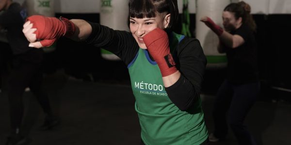 Energetic woman practicing boxing in a Buenos Aires gym with classmates.